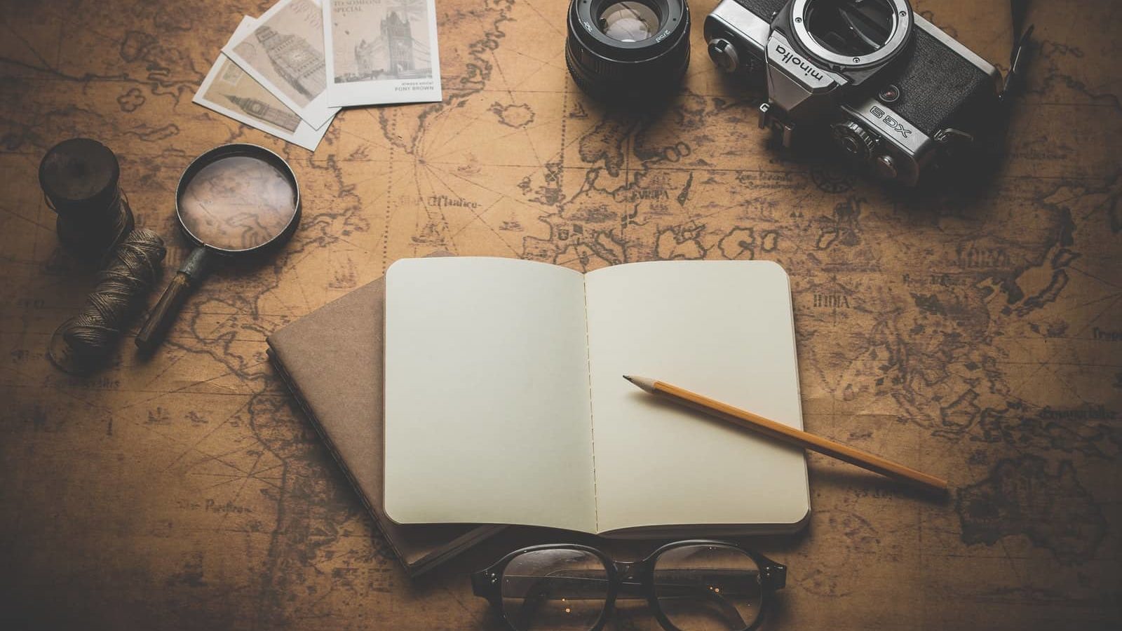 flat ray photography of book, pencil, camera, and with lens