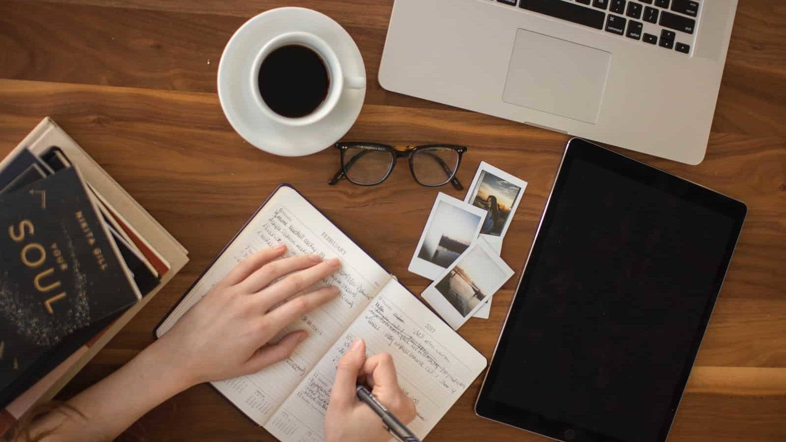 person holding ballpoint pen writing on notebook