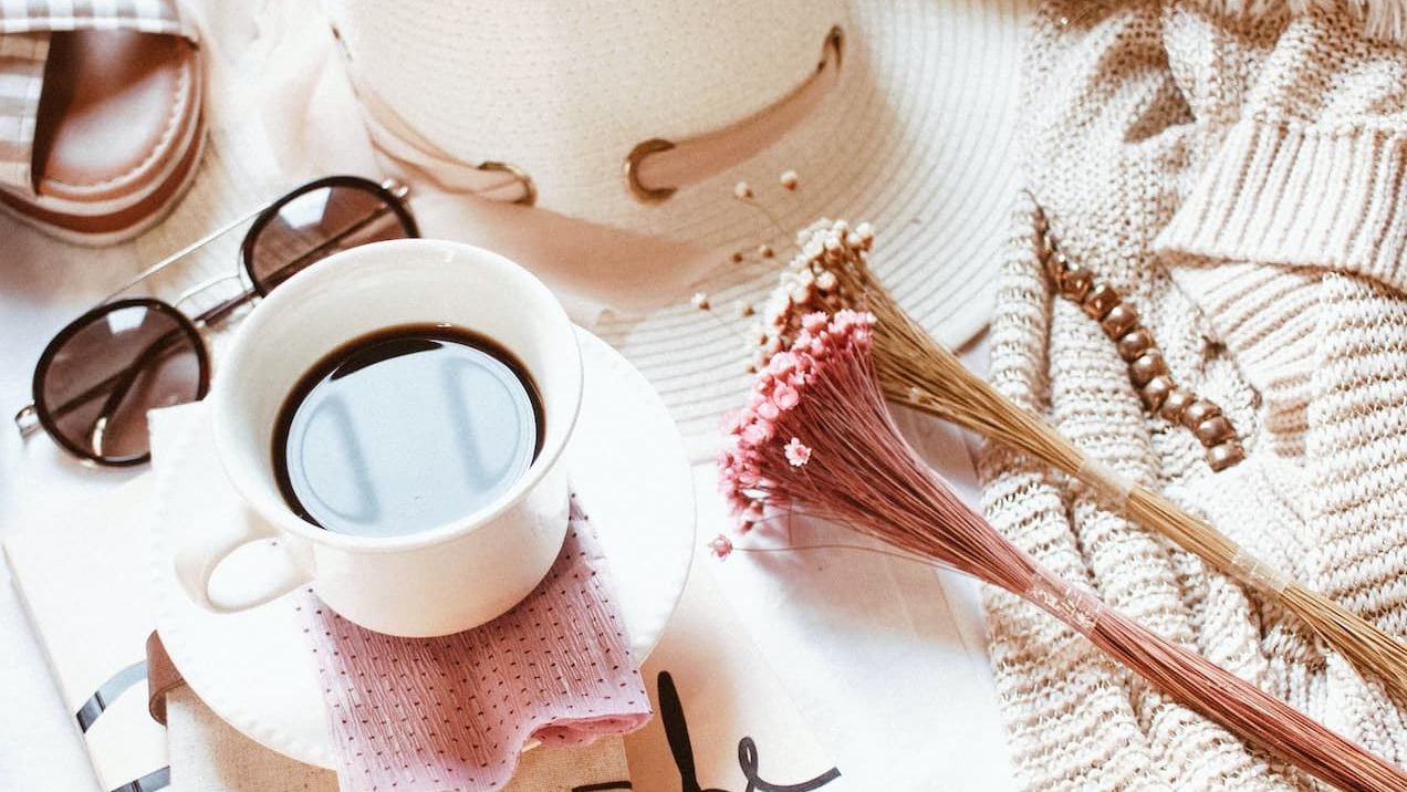 white ceramic mug filled with coffee near brown jacket