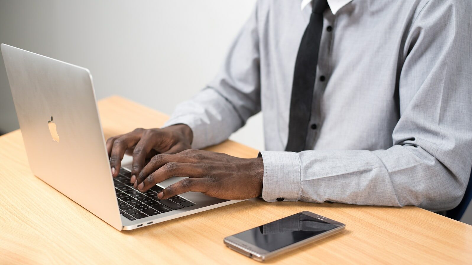 man sits typing on MacBook Air on table