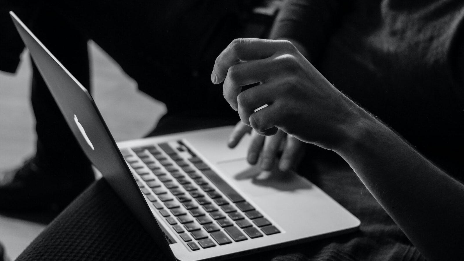 grayscale photo of person using MacBook