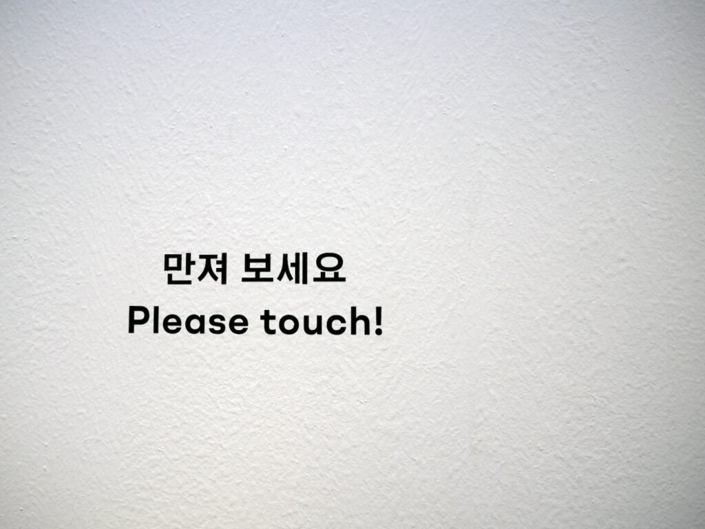 a white wall with a sign that says please touch
