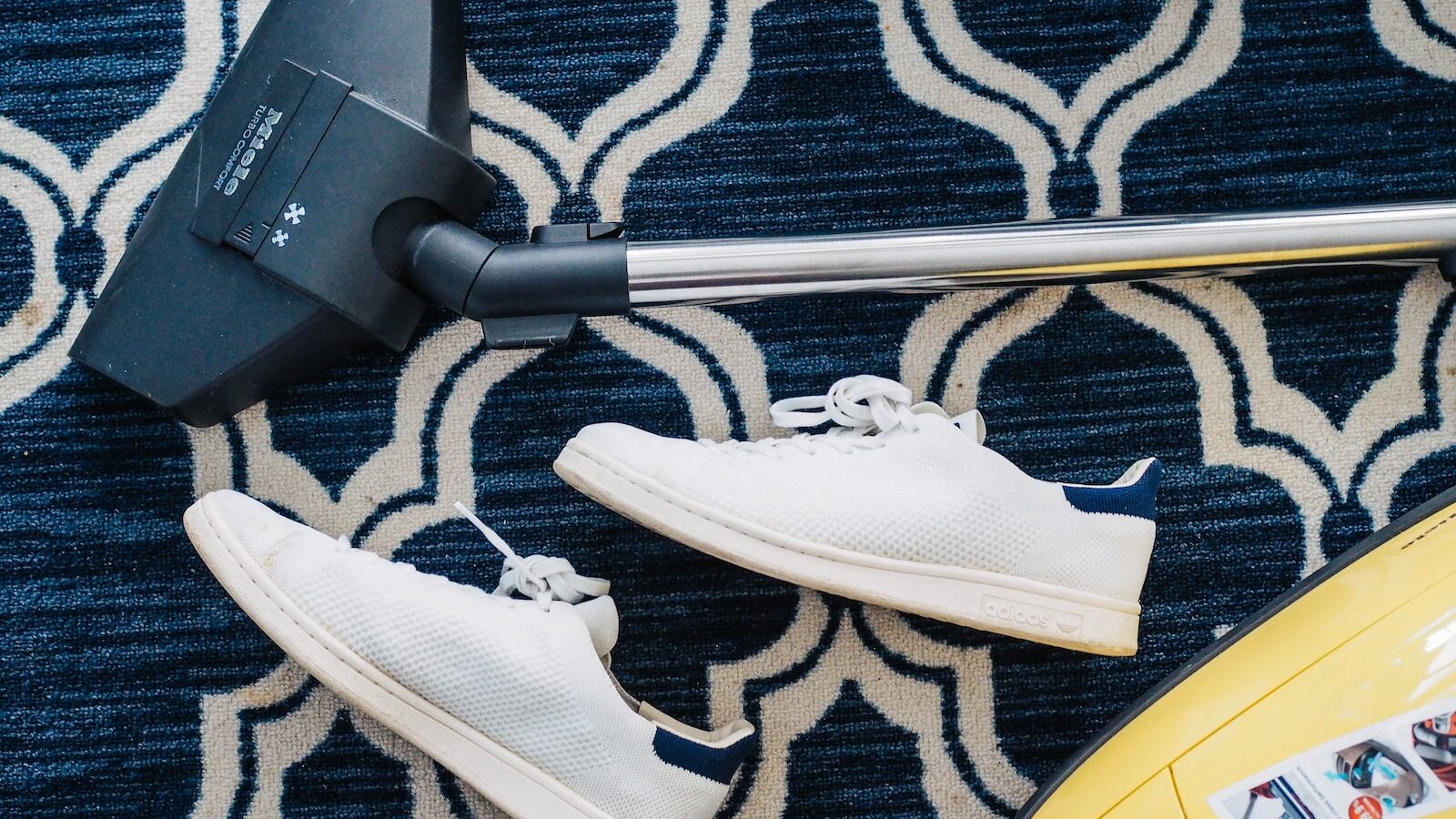 pair of white sneakers beside vacuum cleaner